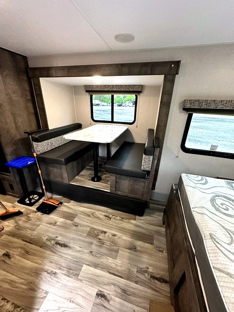 RV rental dinette with booth seating, table, wood-look floor, and windows, offering a cozy mobile living space.