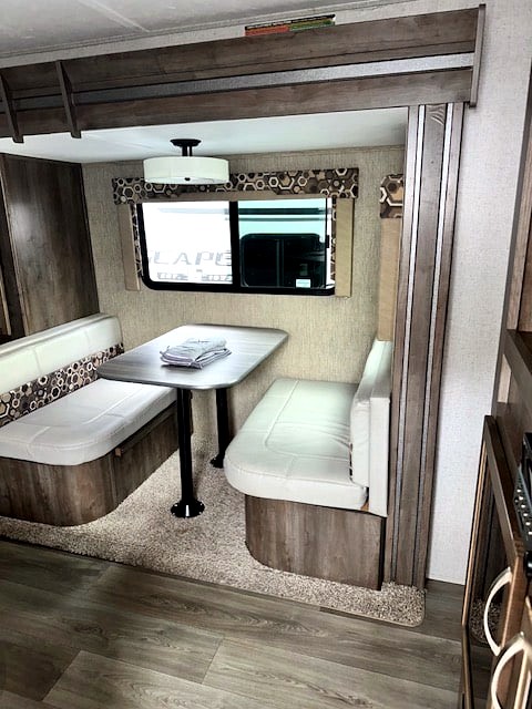 Inside this RV rental, a compact dinette with cushioned benches and a table offers a comfortable dining space.