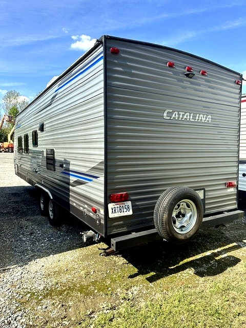 Gray Catalina travel trailer RV rental, with a rear spare tire and blue stripe detail.