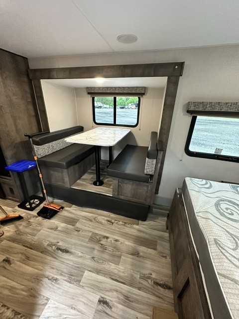 RV rental dinette with booth seating, table, wood-look floor, and windows, offering a cozy mobile living space.