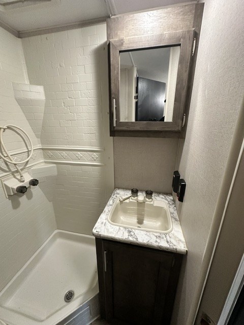 Clean RV rental bathroom featuring a shower, sink with vanity, & mirrored medicine cabinet. Perfect for your travels.