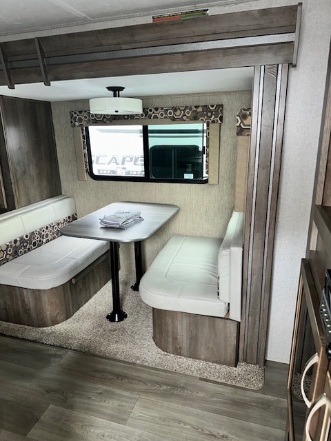 Inside this RV rental, a compact dinette with cushioned benches and a table offers a comfortable dining space.