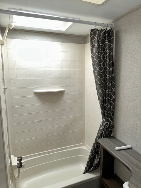 Clean RV rental bathroom with a white tub/shower, patterned grey curtain, and skylight. Ready for your next adventure.