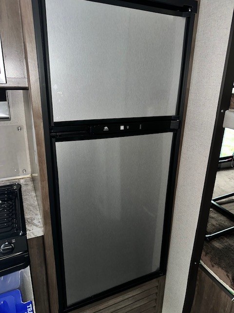 This RV rental's kitchen includes a tall, silver two-door refrigerator/freezer unit, perfect for keeping food fresh on your trip.